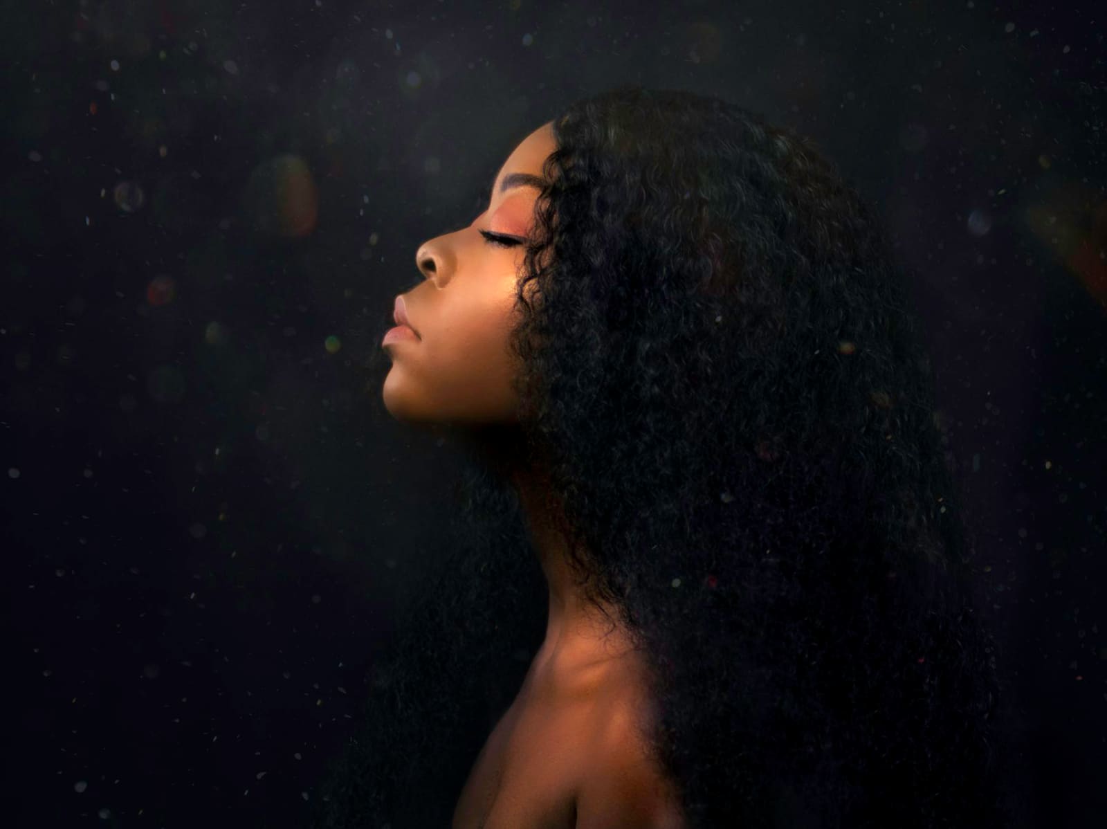 Femme aux longs cheveux lisses, de profil sur fond sombre